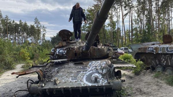 A man walks on top of a damaged Russian tank in Dmytrivka, Ukraine. (Karl Ritter/AP)